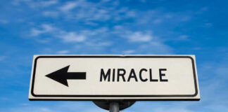 Road sign pointing left saying miracle