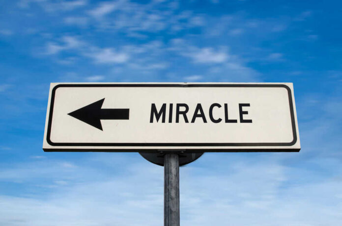 Road sign pointing left saying miracle