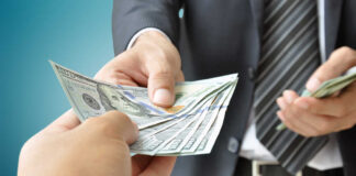 A person handing over a stack of cash to another individual in a suit