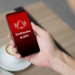 Hand holding a smartphone displaying an earthquake alert notification