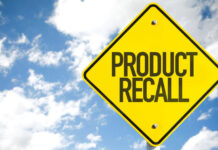 Yellow product recall sign against cloudy sky