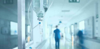 Hospital corridor with IV drip and healthcare worker.