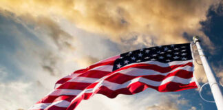 American flag waving against a cloudy sky.