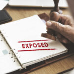 A hand stamping the word 'EXPOSED' on a document