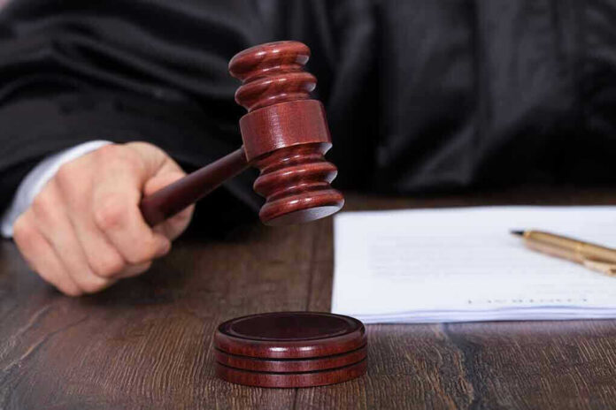 Judges hand holding gavel next to documents.