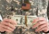Soldier in military uniform holding a bundle of cash