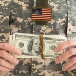 Soldier in military uniform holding a bundle of cash