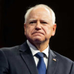 Tim Walz in suit with American flag pin.