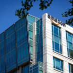 Amazon FLEES Italy Because of THIS! Modern office building with Amazon logo against sky