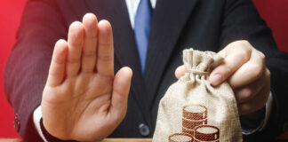 Businessman holding a money bag with a raised hand signaling refusal