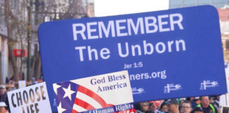 Pro-life marchers holding various anti-abortion signs.
