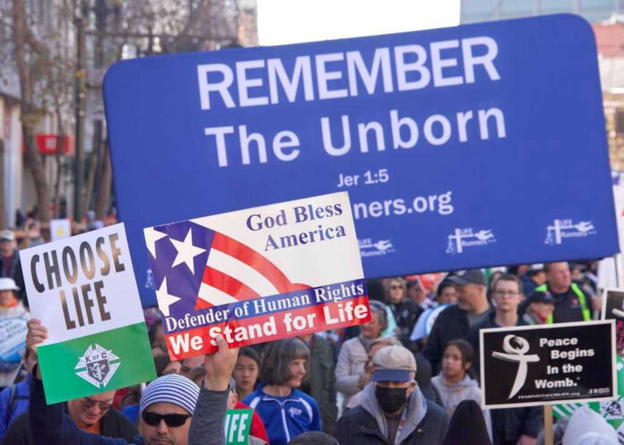 shutterstock_2252807065.jpg Pro-life marchers holding various anti-abortion signs.