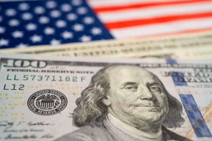 Close-up of a hundred dollar bill in front of an American flag