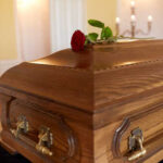 Rock Legend GONE – Music World Mourning A wooden casket with a red rose placed on top