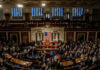 A crowded congressional chamber with members gathered around the central podium