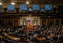 A crowded congressional chamber with members gathered around the central podium