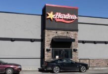 Exterior view of a Hardee's restaurant with a black car parked in front
