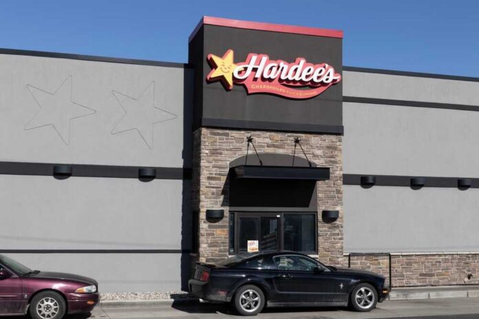 shutterstock_2257545833.jpg Exterior view of a Hardee's restaurant with a black car parked in front