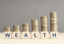 Stacks of coins arranged next to wooden blocks spelling 'WEALTH'