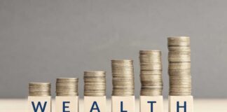 Stacks of coins arranged next to wooden blocks spelling 'WEALTH'