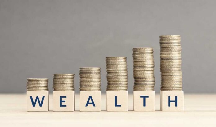 Stacks of coins arranged next to wooden blocks spelling 'WEALTH'