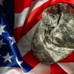 Camouflage military cap resting on an American flag