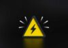 A yellow triangular warning sign with a lightning bolt on a black background