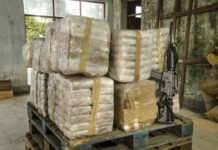Chase Forces STUNNING Cocaine Dump Stacked packages wrapped in plastic next to a rifle in a warehouse setting