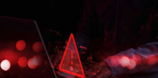 Warning symbol over laptop with user.