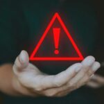 21% Sales Spike HIDES Troubling Reality A hand holding a red warning triangle with an exclamation mark