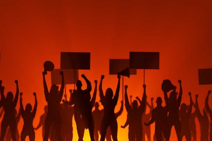 Silhouetted crowd of protesters holding signs against a fiery background