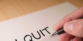 A hand writing 'I QUIT' on a piece of paper