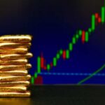 “Portable Wealth” Trend Freaks Out Wall Street Stack of gold bars in front of a stock market chart