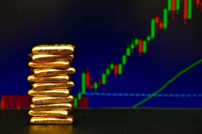 Stack of gold bars in front of a stock market chart