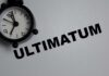 A black alarm clock next to the word 'ULTIMATUM' on a gray background