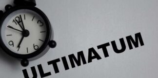 A black alarm clock next to the word 'ULTIMATUM' on a gray background