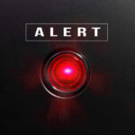 ALERT: Undercover Cop Ambushed Red alert light against black background, text ALERT.