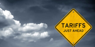 Yellow sign saying tariffs just ahead cloudy sky