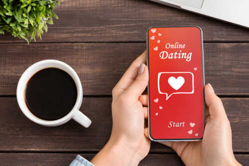Person holding a smartphone displaying an online dating app