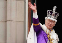 King Charles Speaks During American Revolution Celebration Man in royal attire and crown waving, stone background.