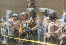 Line of police officers in riot gear standing behind shields
