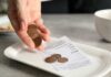 Hand holding coins above a receipt on a plate