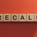 The word 'RECALL' displayed in wooden letter blocks against a red background