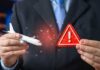 Businessman holding a model airplane and a warning sign