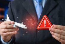 Businessman holding a model airplane and a warning sign