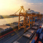 Bridge COLLAPSE Prosecution: SHOCKING Findings Shipping containers and cranes at a port during sunset.