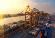 Shipping containers and cranes at a port during sunset.