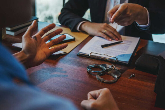 shutterstock_1688525125 Handcuffs and documents on a desk during discussion.