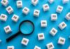 Magnifying glass among cubes labeled job on blue background