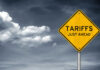 Tariff Bomb Over Smoke Yellow sign saying tariffs just ahead cloudy sky